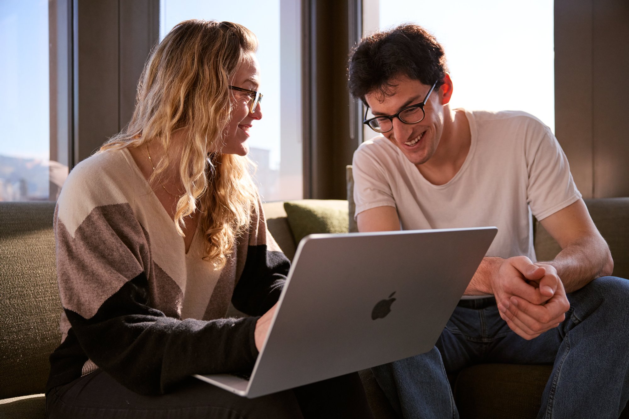 Two people laughing and smiling while collaborating on a laptop.