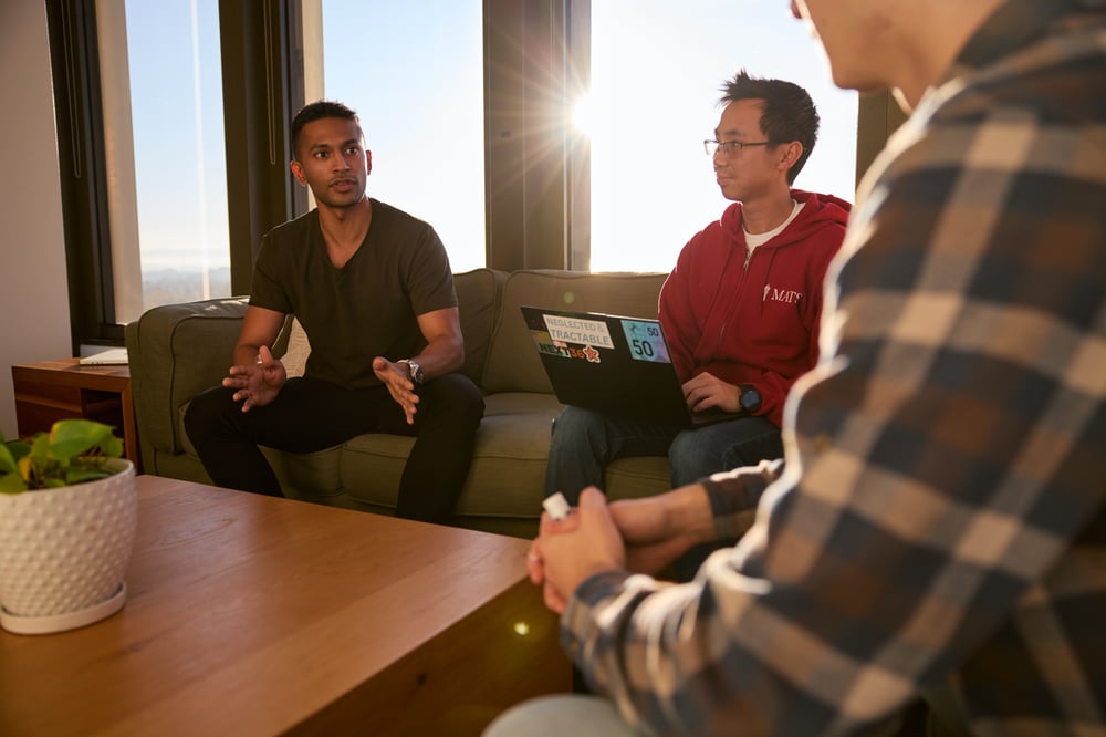 Three people deep in discussion while seated on couches.
