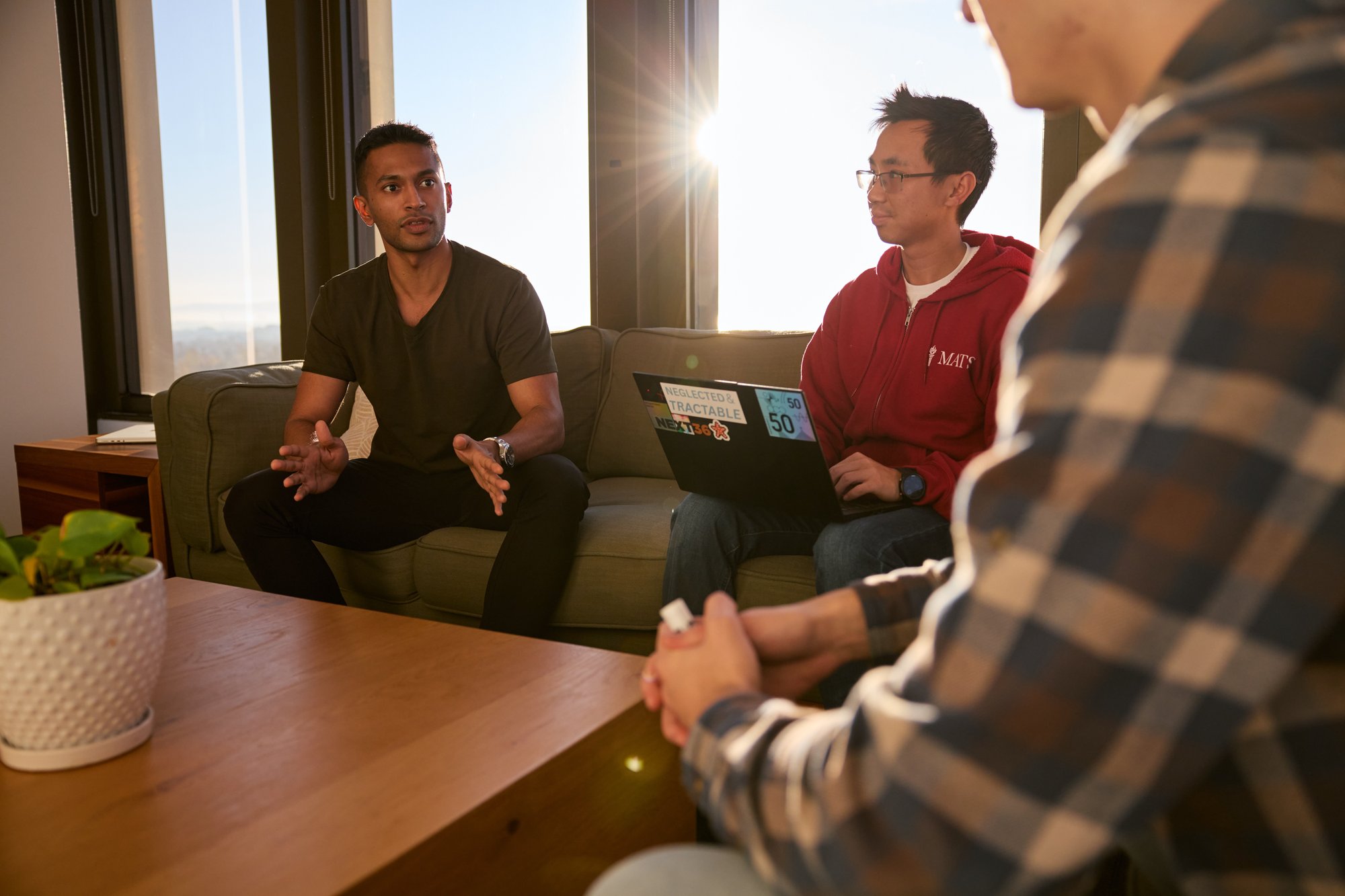 Three people deep in discussion while seated on couches.