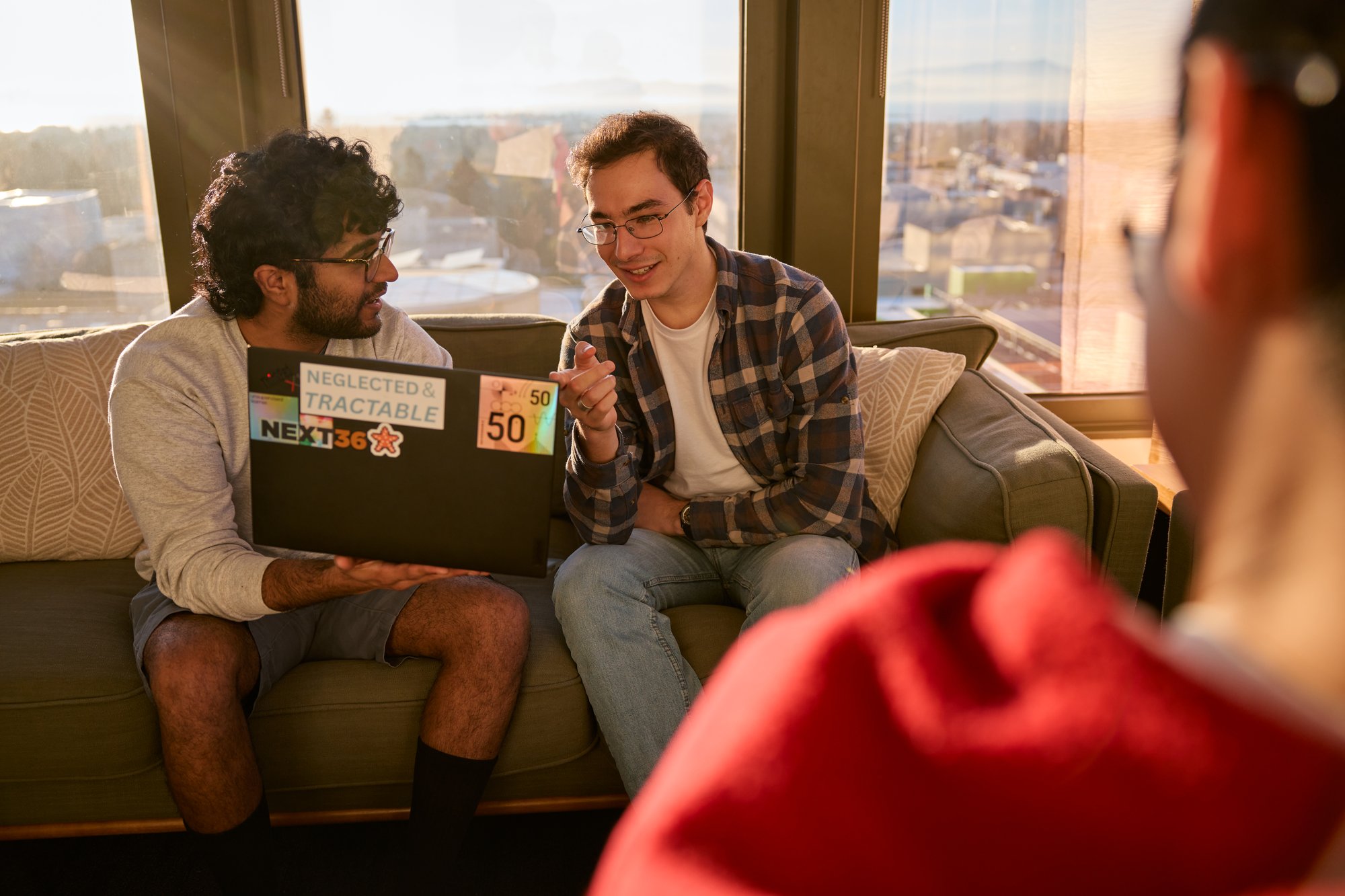 Three researchers collaborating around one laptop.