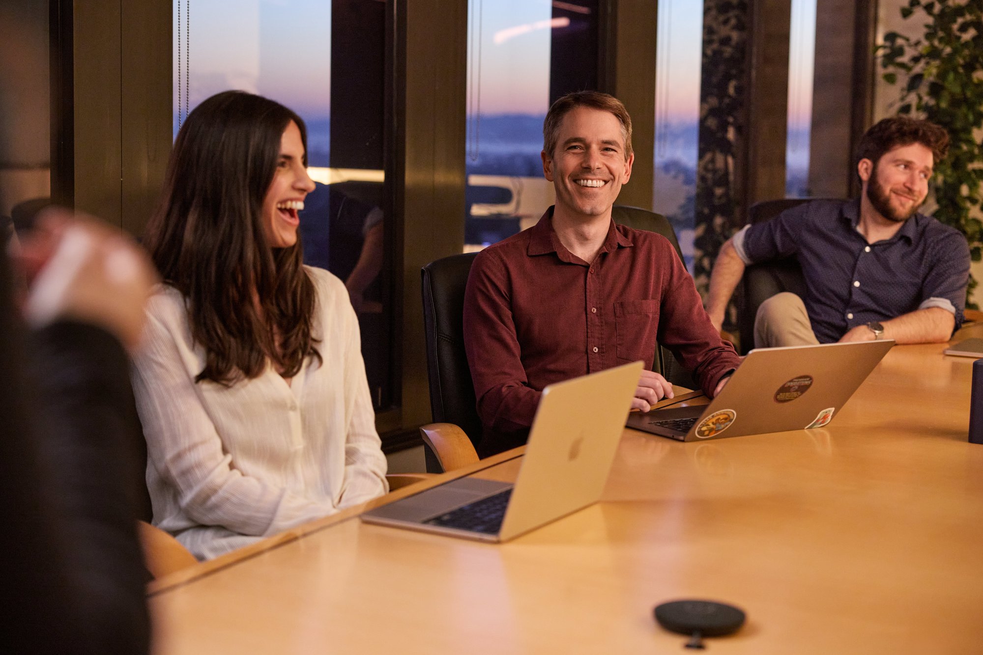 Three people laughing and talking around a table.