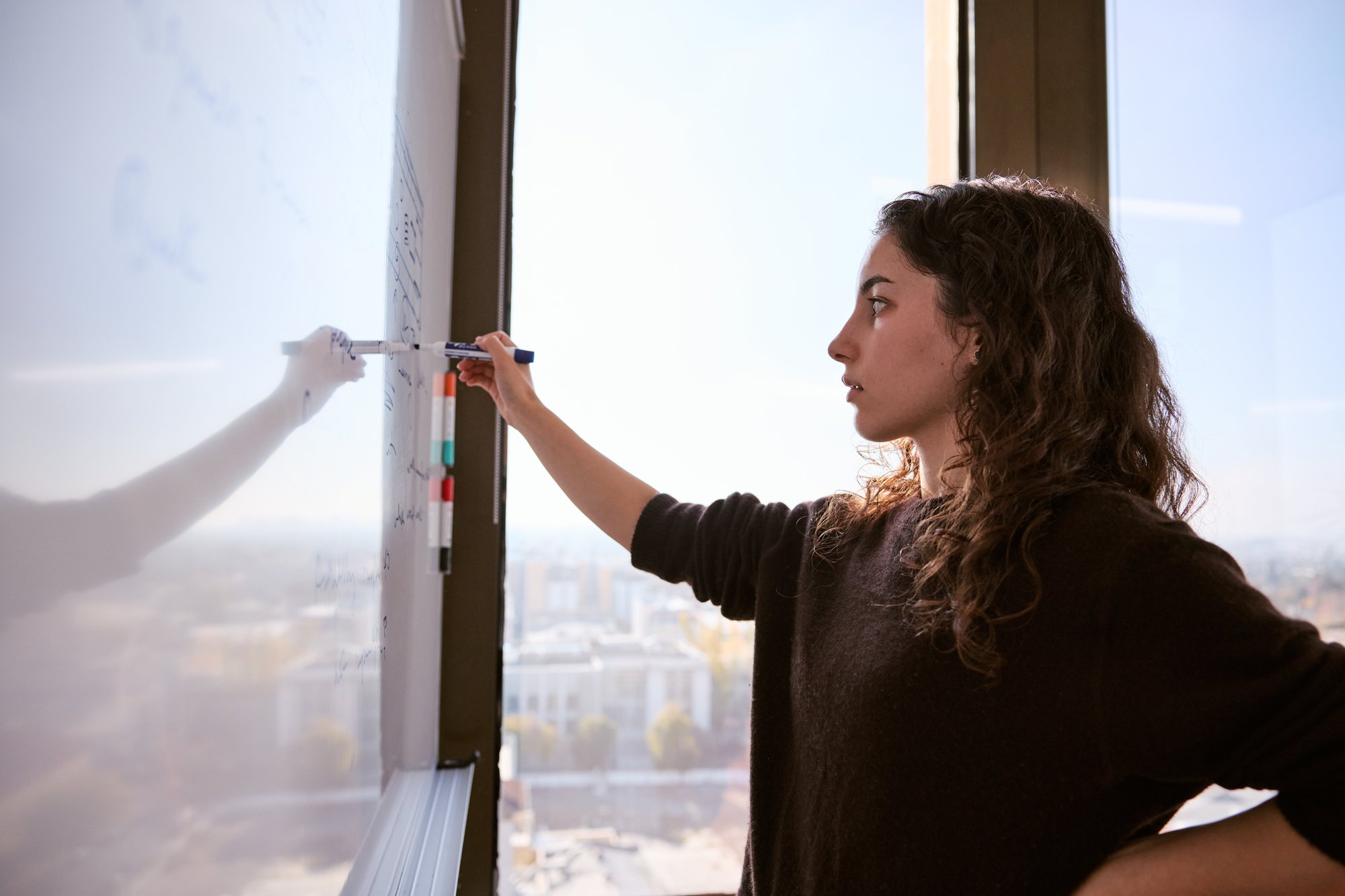 One person writing on a whiteboard.