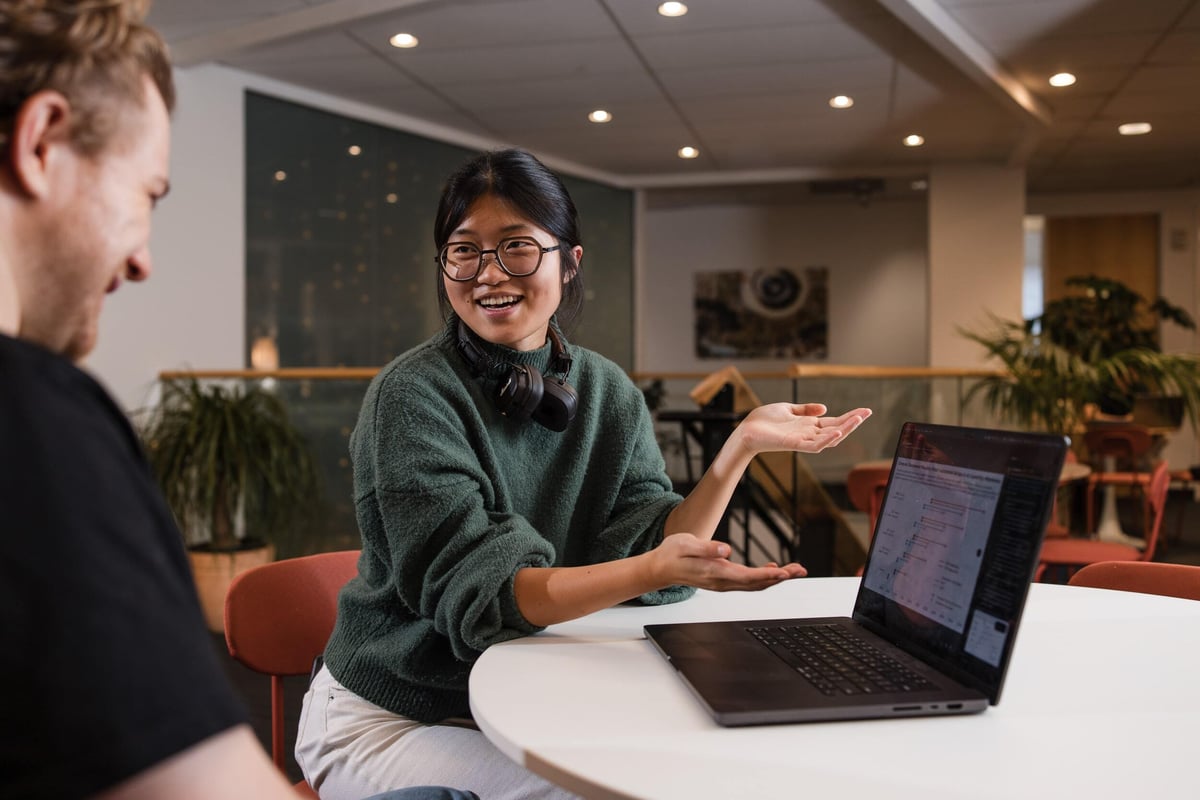 Two people smiling and talking while seated at a table.
